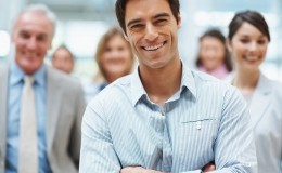 Confident smiling business man with his team at the back