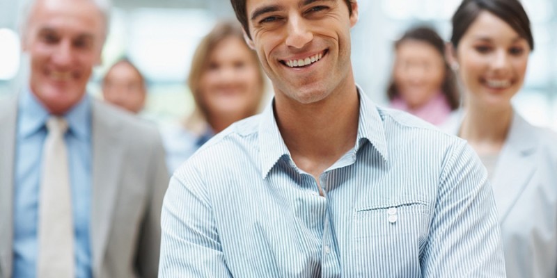 Confident smiling business man with his team at the back